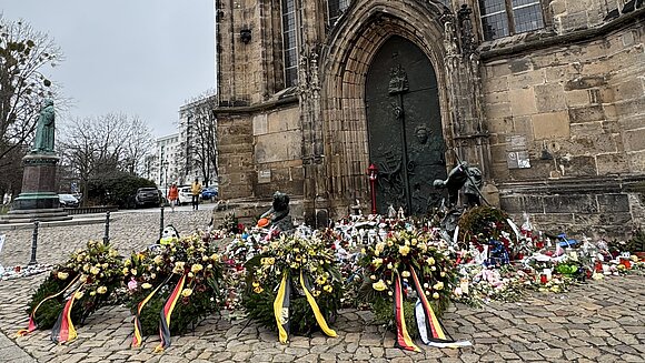 Blumen und Kränze vor der Magdeburger Johanniskirche.