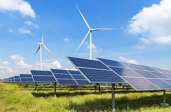 Windräder und Solarpanele auf einem Feld